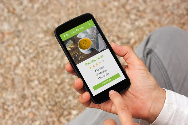 手里拿着食品中的应用的智能手机屏幕上的模拟了 — 图库照片
