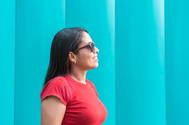 Genç ve güzel bir kadın gündelik giyinmiş, gülümsüyor, yan tarafa bakıyor ve düşünüyor..