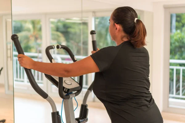 Woman performing workout on elliptical trainer at home