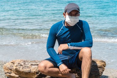 Tropik bir plajda maske takan genç bir adamın portresi.