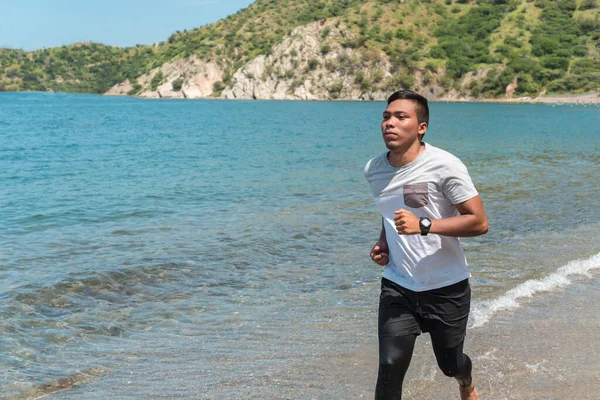 Denize ya da okyanusa yakın tropikal bir kumsalda koşuyor..