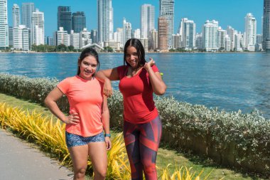 Spor kıyafetli iki genç kadın güneşli bir günde birlikte antrenman yaptıktan sonra gülüyorlar.