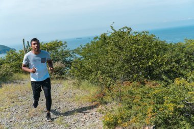 Genç bir adam dağda koşuyor.