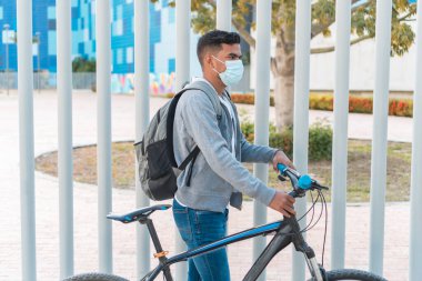 Tıbbi maskeli ve bisikletli adam parkta.