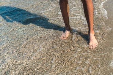 Temiz suda duran bir adamın ayaklarının arkasını kapatın.