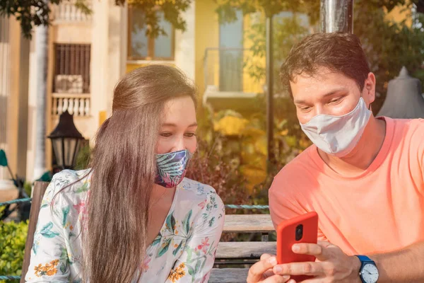 Pareja Parque Usando Smartphone Usando Máscaras Faciales Respetando Distanciamiento Social — Foto de Stock