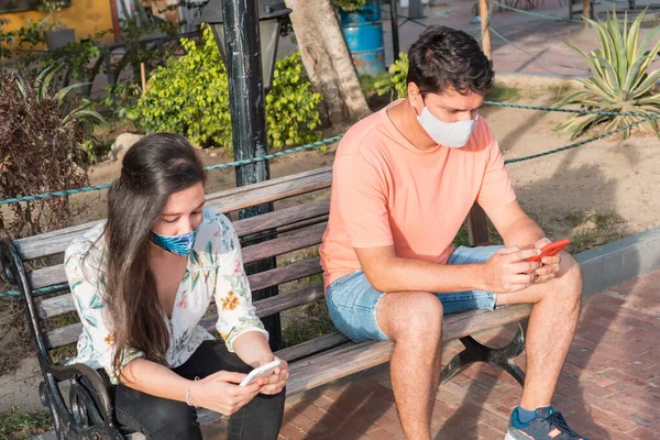 Hispanic Par Parken Med Hjälp Smartphone Bär Ansiktsmasker Och Respektera — Stockfoto