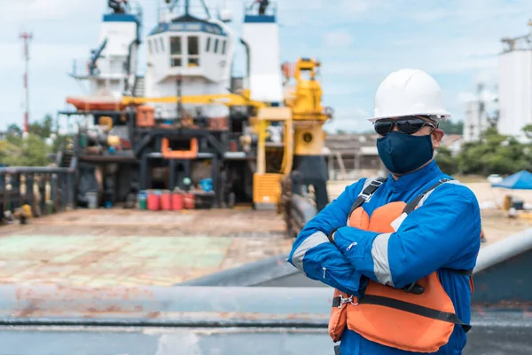 Deck officer with protective mask on ship deck, with PPE personal protective equipment