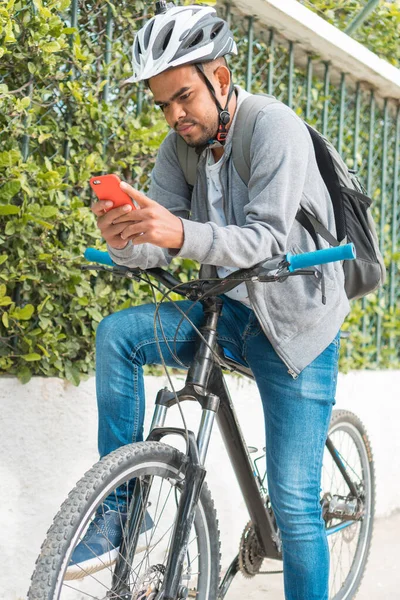 公園の自転車に座ってハンドルにもたれかかって携帯電話を確認してた — ストック写真