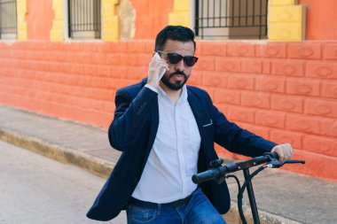 Elektrikli scooterlı ve akıllı telefon kullanan zarif bir genç.