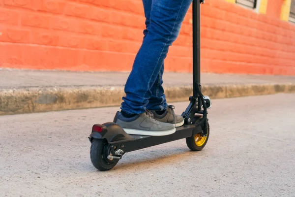 男は街の通りでレンタルした電動スケートボードに乗る 人は輸送手段として電動スケートボードを使用しています — ストック写真