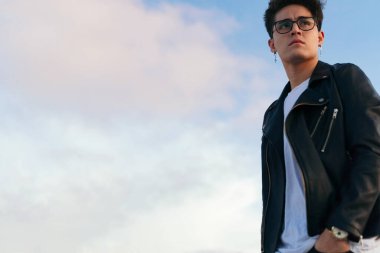 Ciddi bir genç adam şehirde dikilirken gözlerini kaçırıyor..