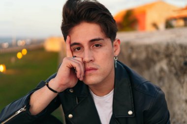 Açık havada üzgün, yakışıklı bir gencin yakın plan portresi..