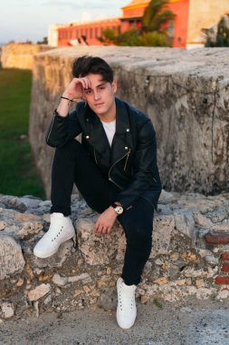 Dışarıda oturan yakışıklı bir gencin yakın plan portresi..