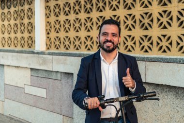 Şehirde elektrikli scooter kullanan, ceketli sakallı bir adam.