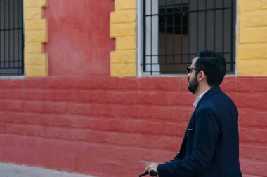 Genç adam şehirde scooter kullanıyor.