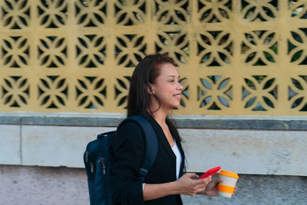 ラティーナの実業家は午前中に仕事に行く 女性は携帯電話とホットコーヒーを持って仕事に歩いた — ストック写真