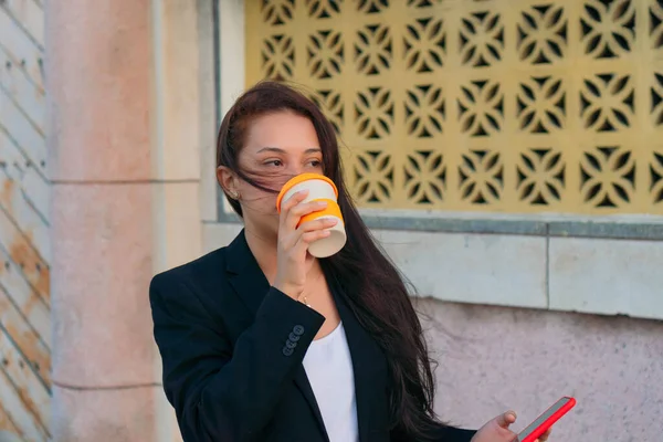 若い女性がコーヒーを飲んで携帯電話を持ってる — ストック写真