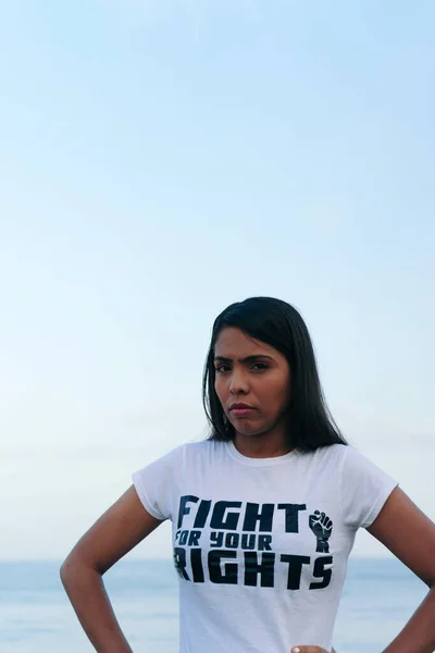 A beautiful young woman belonging to the feminist movement wears a message on her T-shirt.