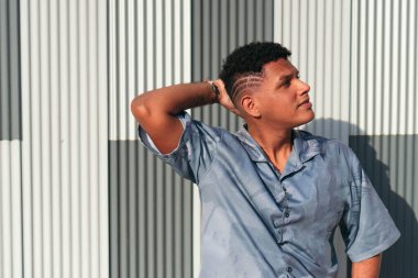 Gri bir duvara yaslanmış rahat bir adamın portresi.