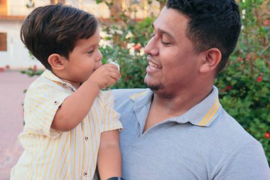 Baba şeker yerken oğlunu kucağında tutuyor.