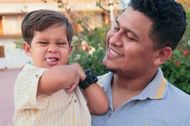 Latin baba ve oğlu parkta dikiliyorlar.