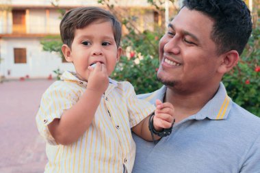 Hispanic father and son spend a day together in the park clipart