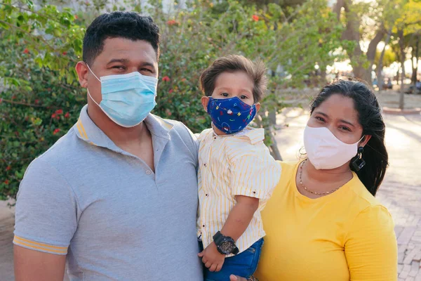 Family with protective mask holding baby in park