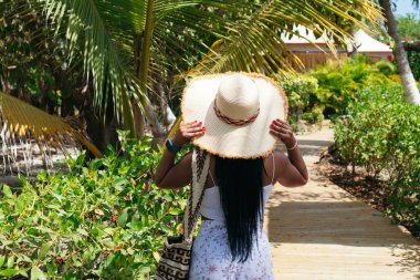 Doğada hasır şapka takan bir kadının arka görüntüsü..