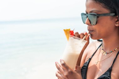Genç ve güzel bir kız sahilde kokteyl içiyor. Yaz Saati.