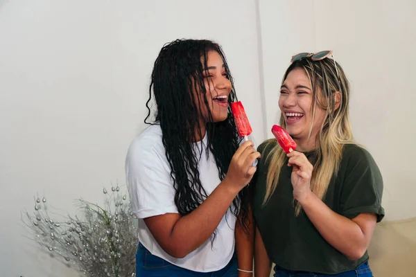 Two best friends having ice cream together at home. Young women eating ice cream and laughing.