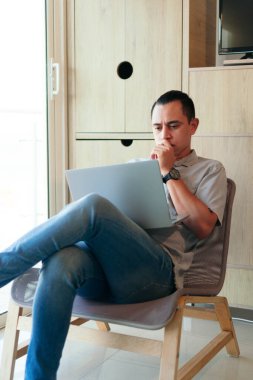 İspanyol adam evinin oturma odasında dizüstü bilgisayar kullanıyor.