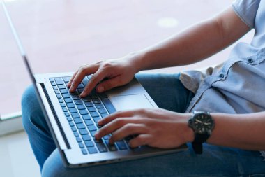 Oturma odasında otururken dizüstü bilgisayar kullanan bir adam