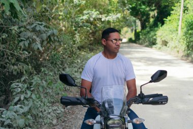 Parkta motosikletli bir motorcunun portresi.