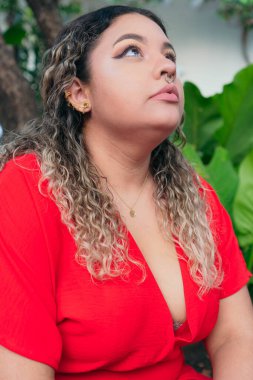 Ciddi artı boyda, kırmızı elbiseli genç bir model, parkta bir kadın..