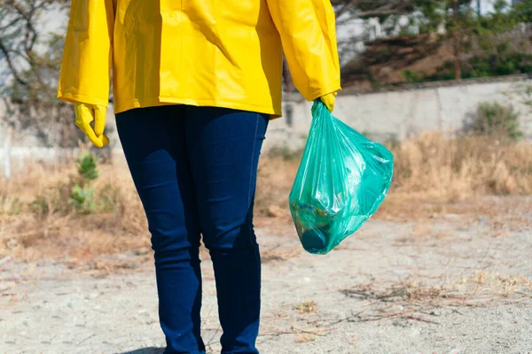 Young woman holding a green bag in the park. Concept of cleanliness