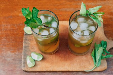 Dondurulmuş alkollü mojito, buzlu nane yaprakları ve tahta üzerinde dilimlenmiş limon.
