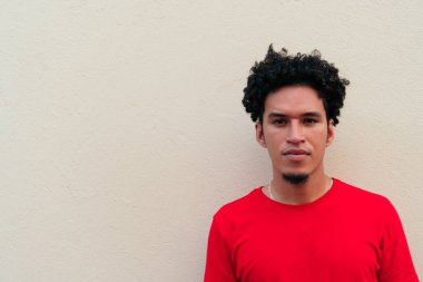 Genç kıvırcık saçlı kız Gri bir duvarın önünde duruyor