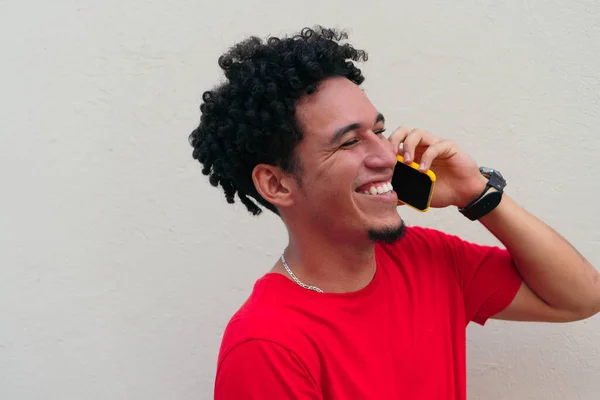 Gri Bir Duvarın Önünde Akıllı Telefonla Konuşan Gülen Genç Bir — Stok fotoğraf