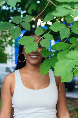 Parktaki bir ağacın arkasında bir kadının portresi.