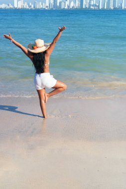 Okyanusun önünde elleri havada duran bir kadın.