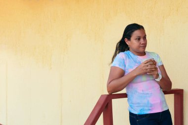 Orta yaşlı bir kadın uzaktan bakarken evde kahve içiyor.