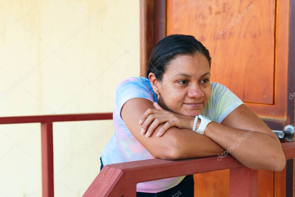 Mature woman outside home while looking into the distance. Middle aged woman relaxing outside home.