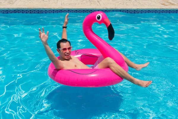 男は楽しいを持っていますFucsia Flamingoインフレータブルフロートでプール — ストック写真