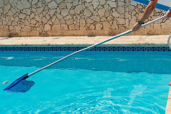 Unrecognizable man cleaning the pool in the summertime