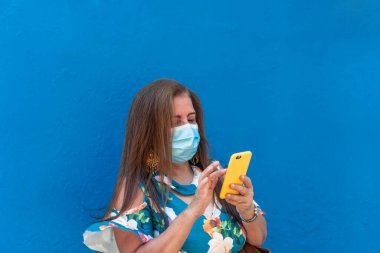 Sokakta telefonunu kullanan koruyucu maskeli yaşlı bir kadın..