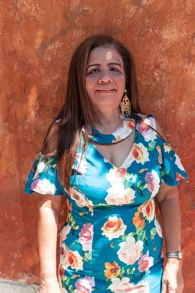 Portrait of an older Hispanic woman with long hair and smiling.