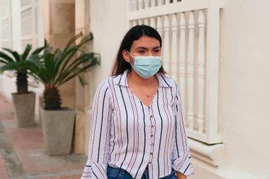 Karantinadan sonra şehirde dolaşan genç bir kadın. Alışveriş çantalı ve tıbbi maskeli bir kadın..