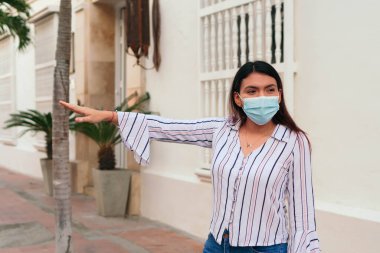 Elinde alışveriş poşetleri olan ve taksi çağırırken gülümseyen bir kadın. Uzun bir alışveriş gününden sonra taksi bekliyorum..