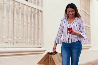 Güzel bir kadın şehirdeki akıllı telefondan mesaj atıyor.